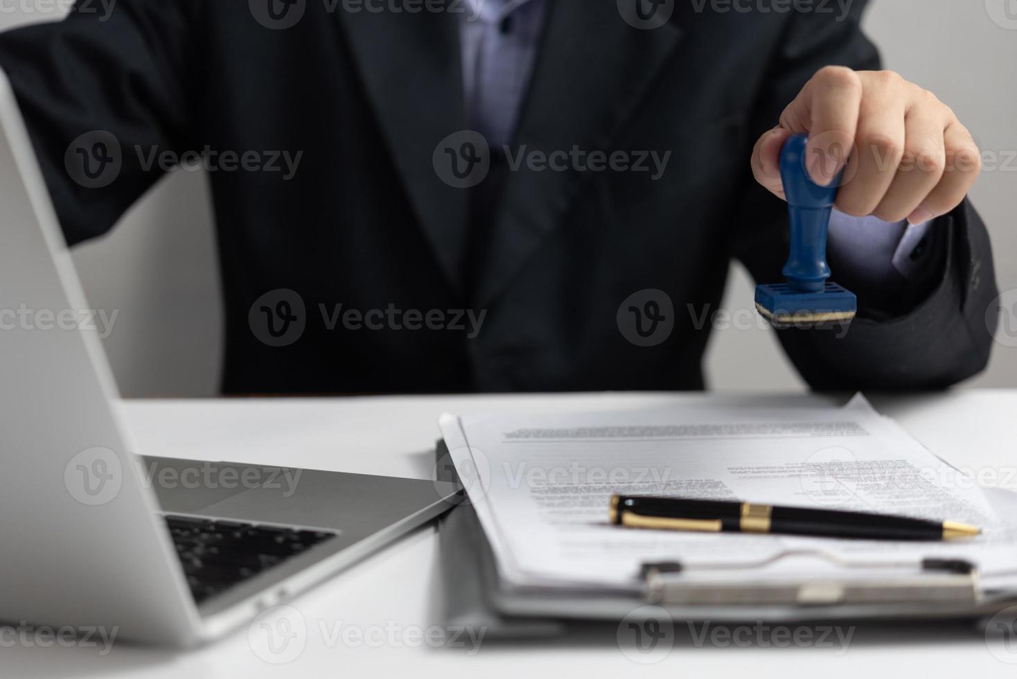 Man stamping approval of work finance banking or investment marketing documents on desk. photo