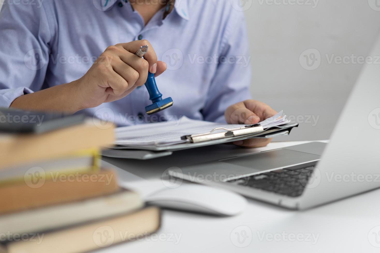 Man stamping approval of work finance banking or investment marketing documents on desk. photo