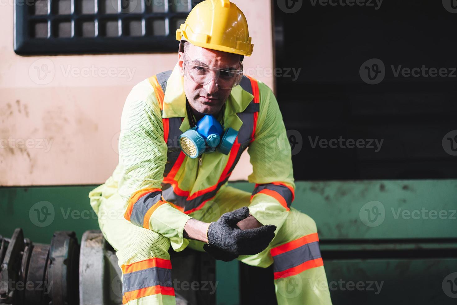Portrait of factory worker man wearing hardhat and safety protection  looking at camera sitting in gloves to prepare for work photo