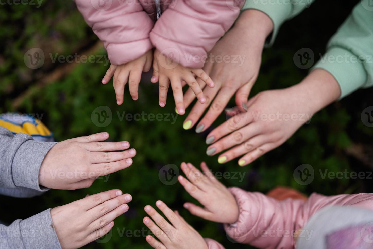 Close up of hands and fingers of mother with kids in spring forest background. photo