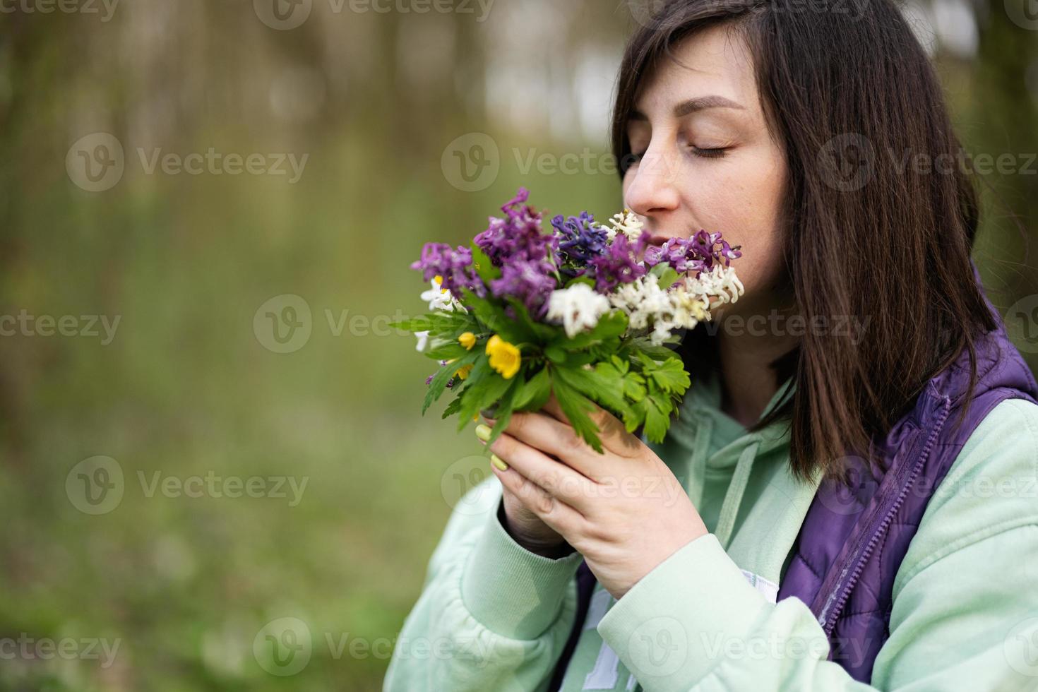 Portrait of woman with spring bouquet of flowers on forest. Outdoor leisure concept. photo