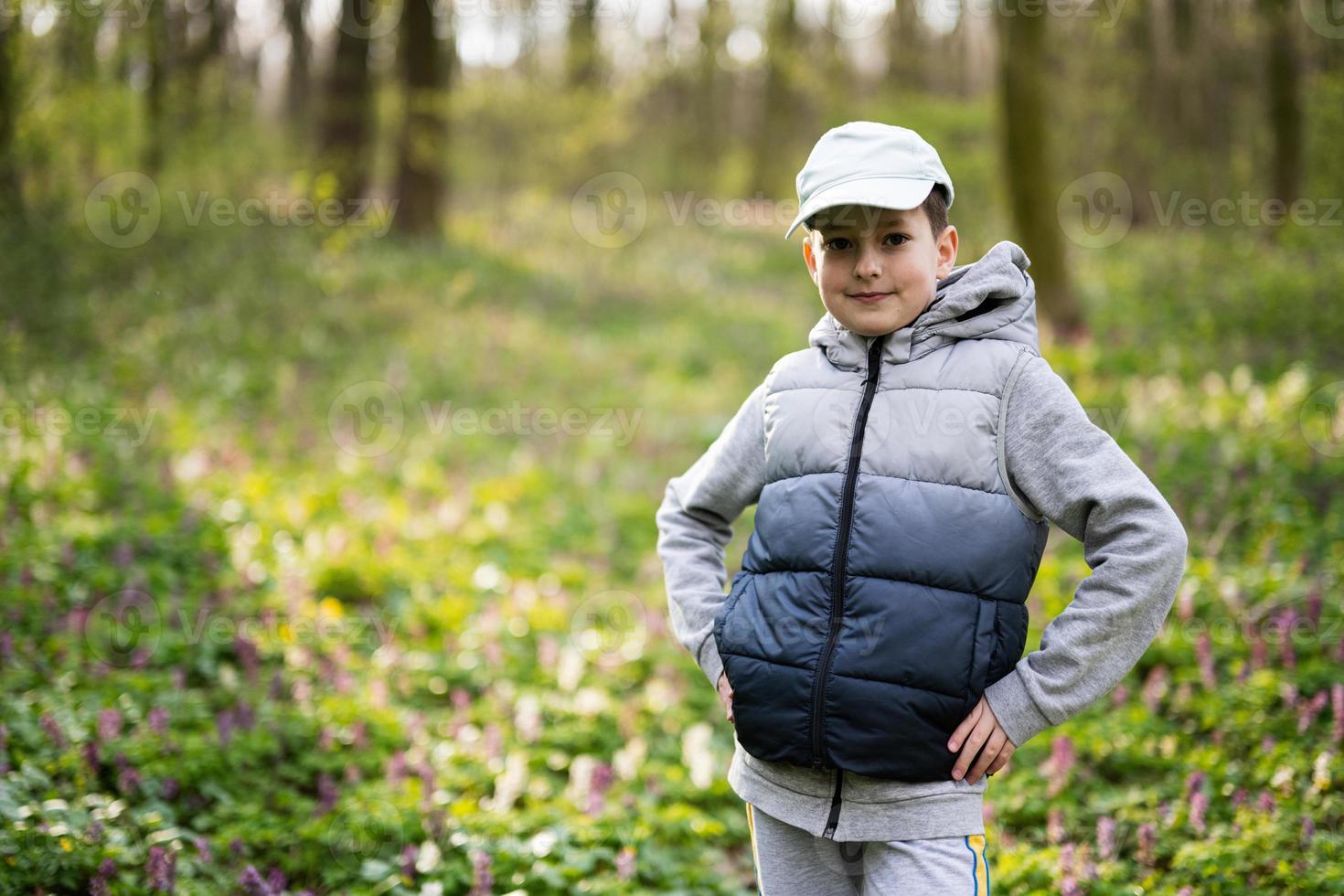 Portrait of boy in cap on sunny forest. Outdoor spring leisure concept. photo