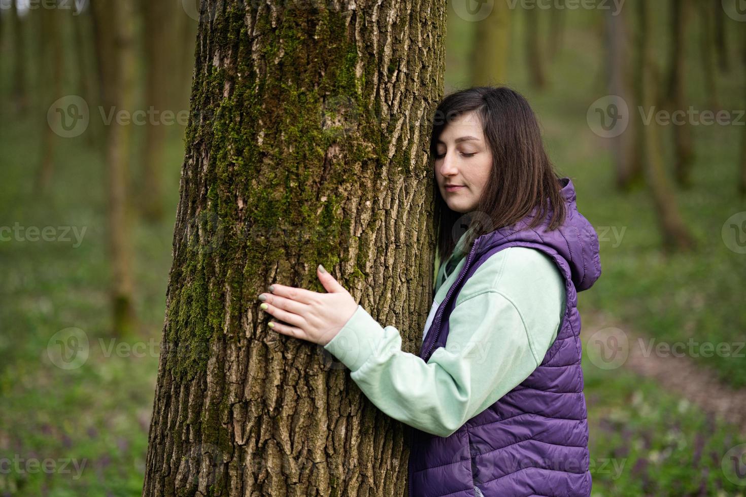 retrato de mujer abrazo y apoyarse a árbol en bosque. amor a naturaleza. foto