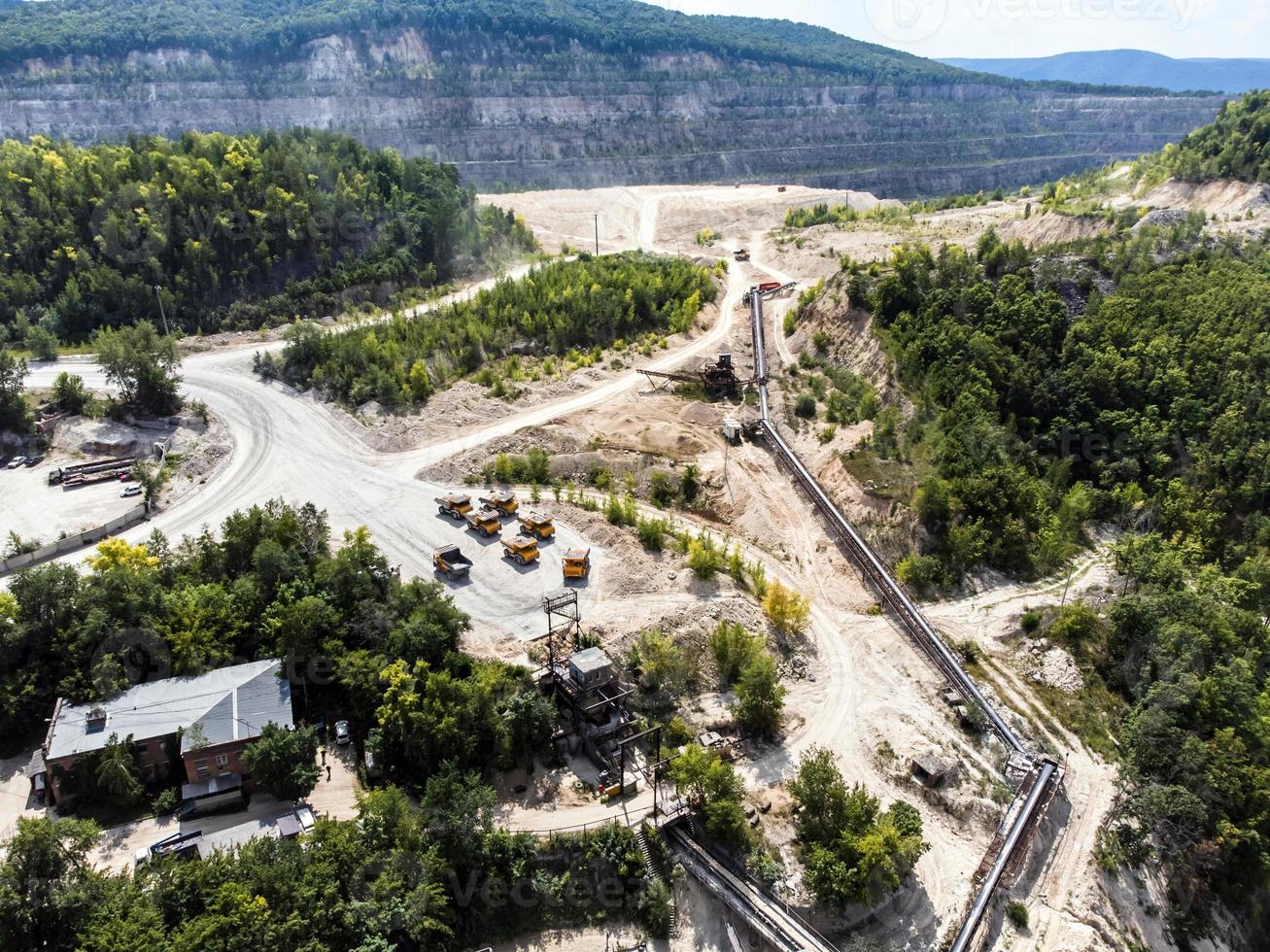 Aerial view of mining trucks queuing to be unloaded onto a conveyor system. photo