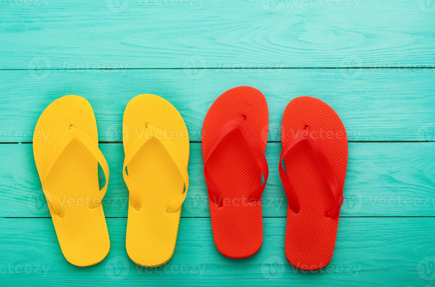 Chanclas de colores sobre fondo de madera azul con espacio de copia. vista superior foto