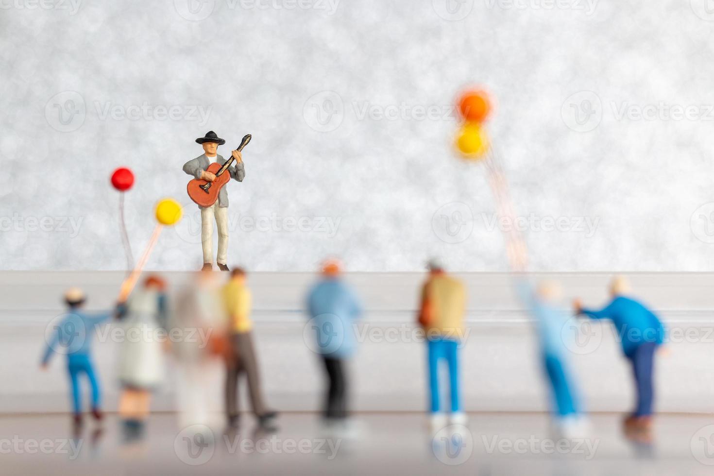 miniatura músico jugando un guitarra en escenario, mundo música día concepto foto