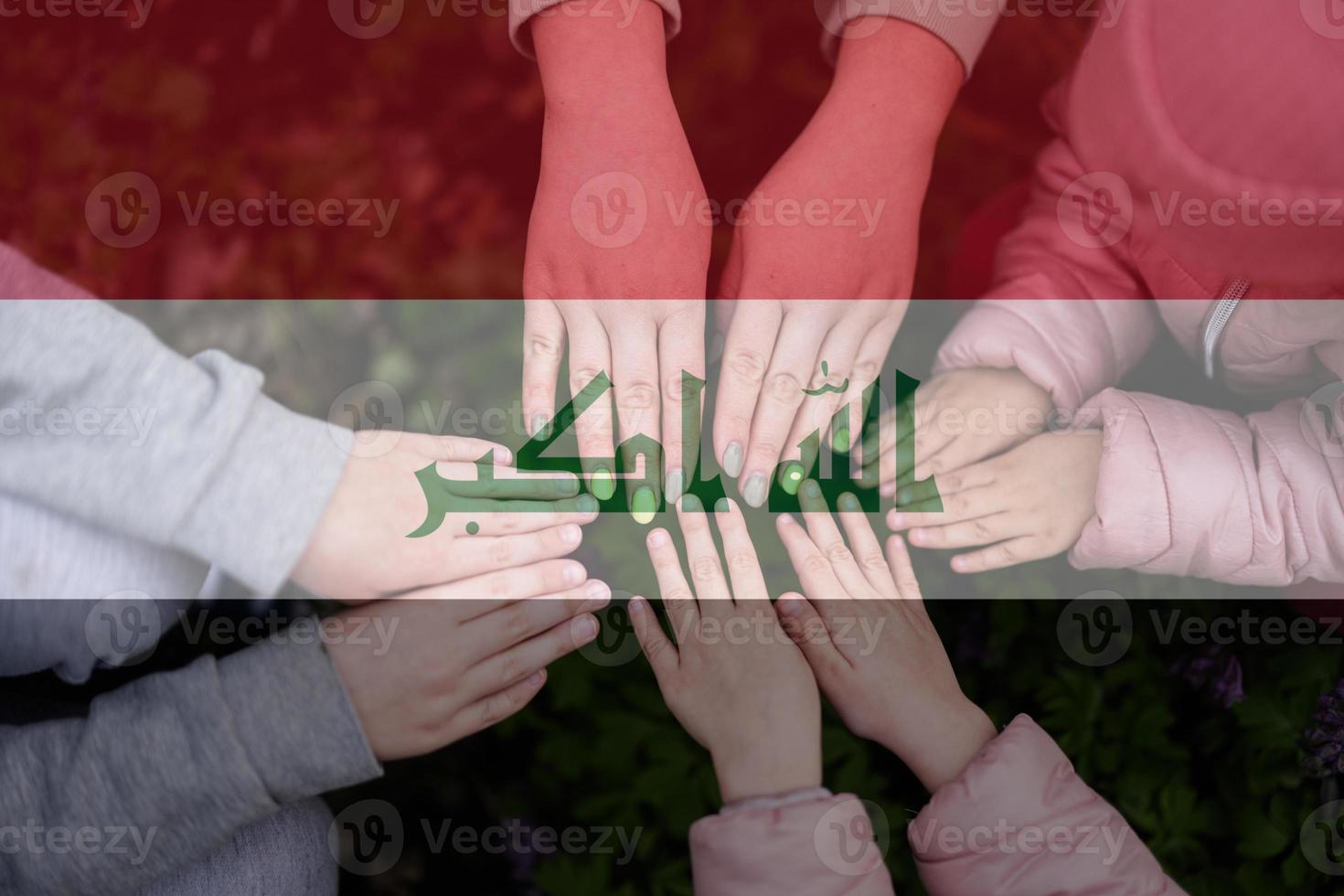 Hands of kids on background of Iraq flag. Iraqi patriotism and unity concept. photo