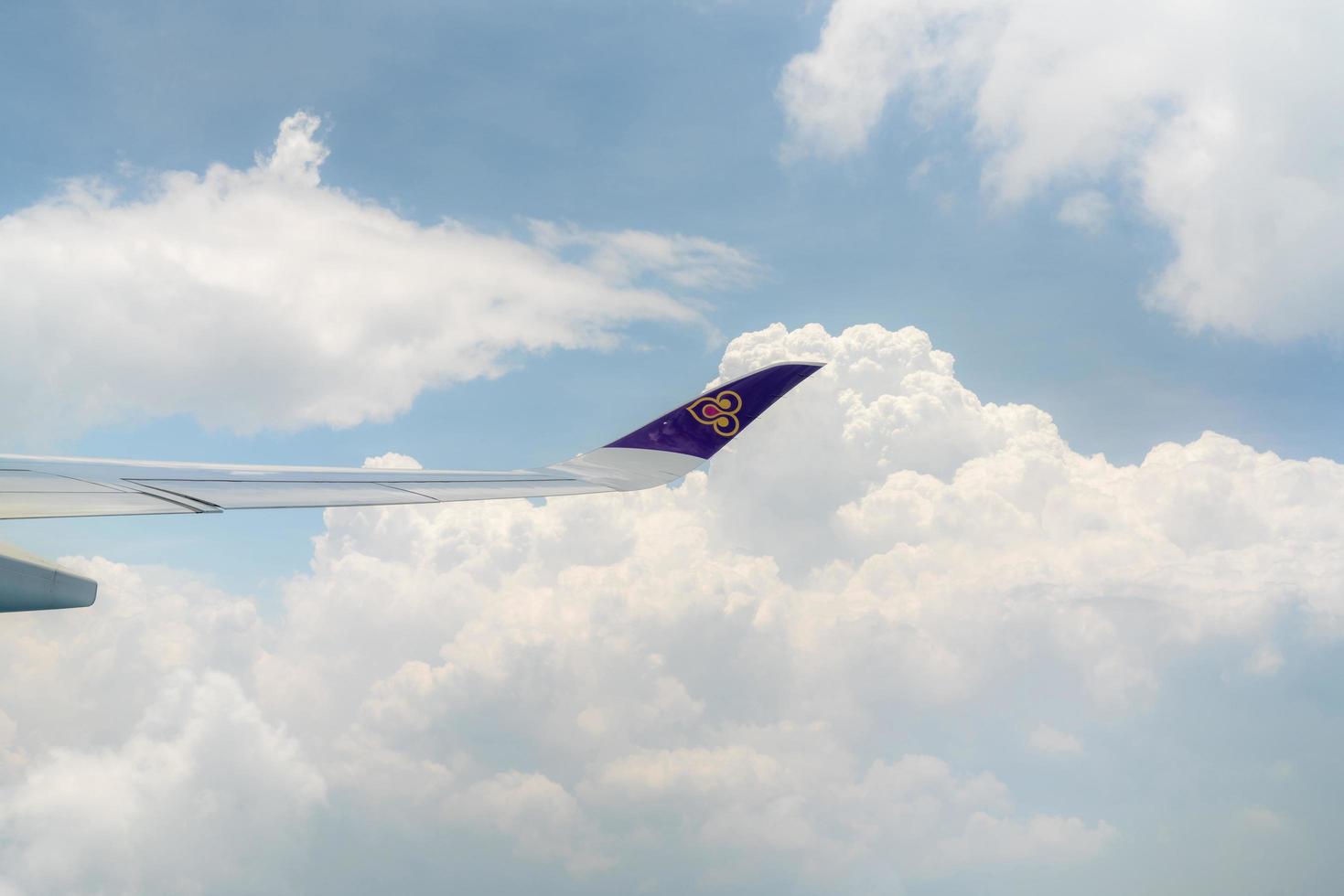 BANGKOK, THAILAND-OCTOBER 19, 2019 Plane wing of Thai Airways Airlines. Passenger plane. Wing of plane over white fluffy cumulus clouds. Airplane flying on blue sky. Scenic view from airplane window. photo