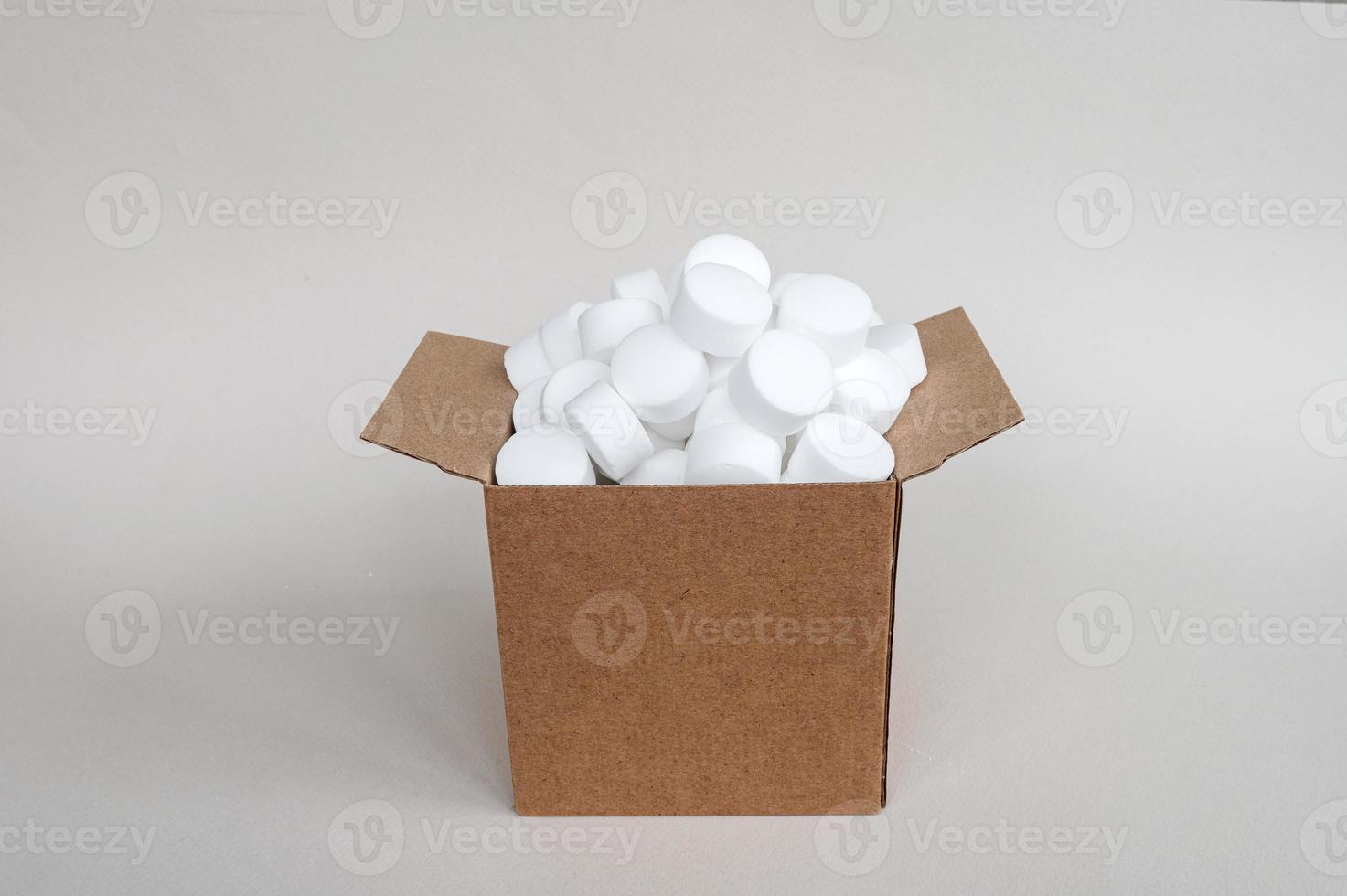 blanco redondo lavavajillas sal tabletas en un caja. un conjunto de blanco cápsulas en un abierto caja foto