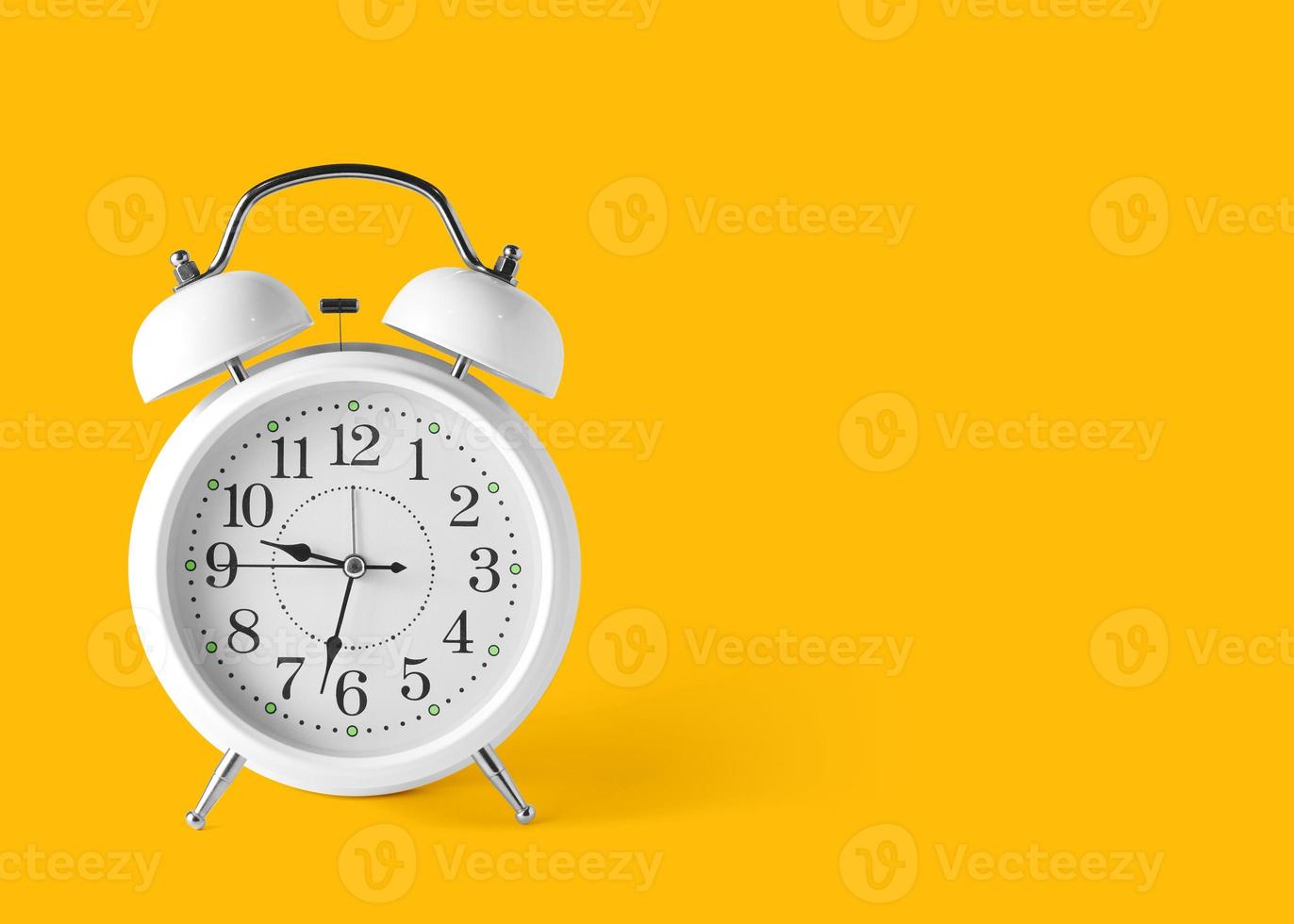 An antique white alarm clock on the floor with a bright yellow background in pastel colors. minimal creative concept . and copy space for your text. Minimal idea concept photo