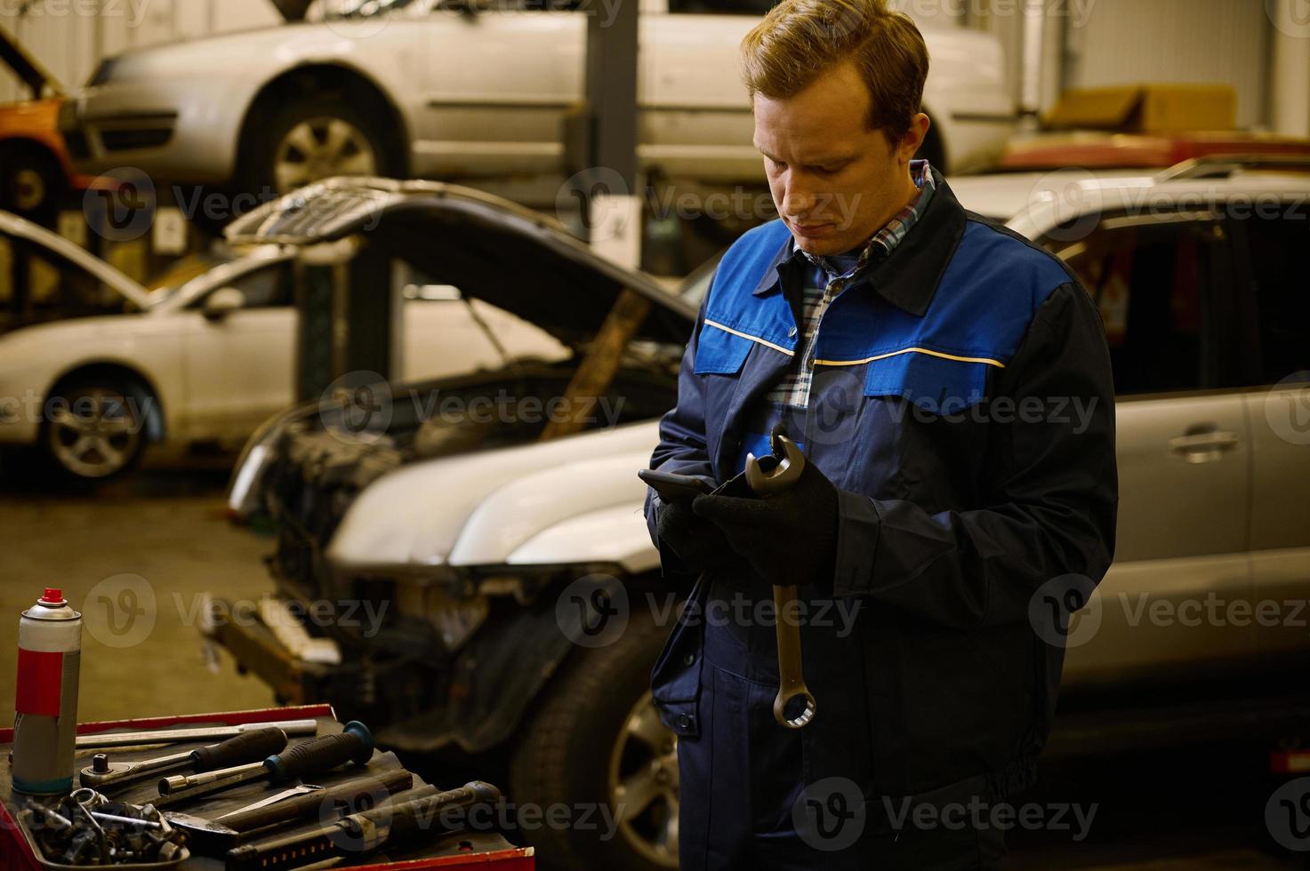 Technician, mechanic in professional uniform with wrench at repair shop. Automobile warranty repair and maintenance concept photo