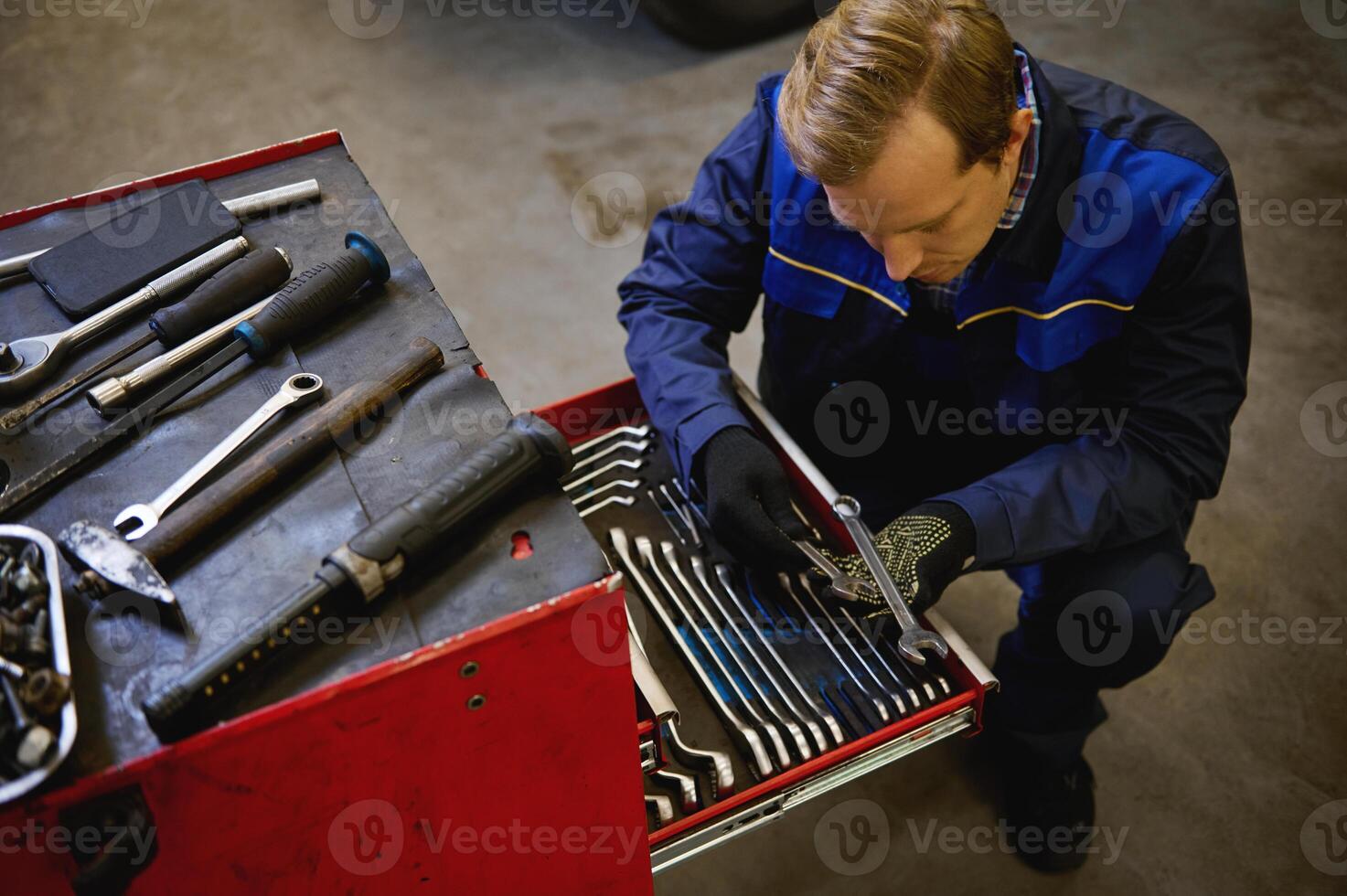 Top view of a car mechanic, technician taking wrench from the box in the repair shop garage. Warranty repair and car maintenance concept photo