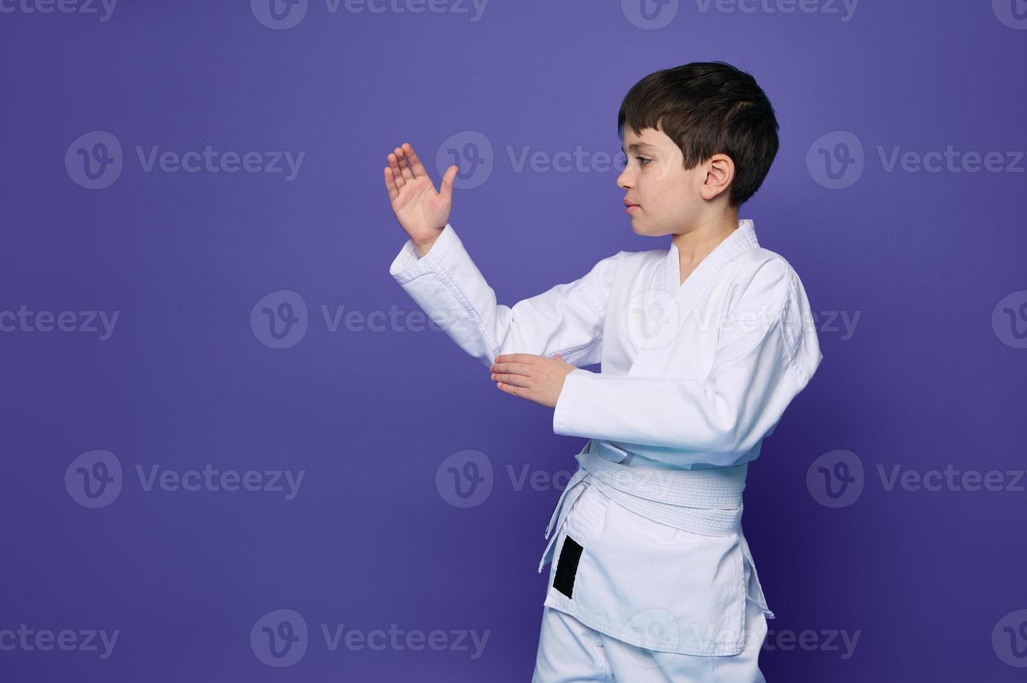 Charming confident Oriental martial arts wrestler practicing martial skills isolated on purple background with copy space for advertising text photo