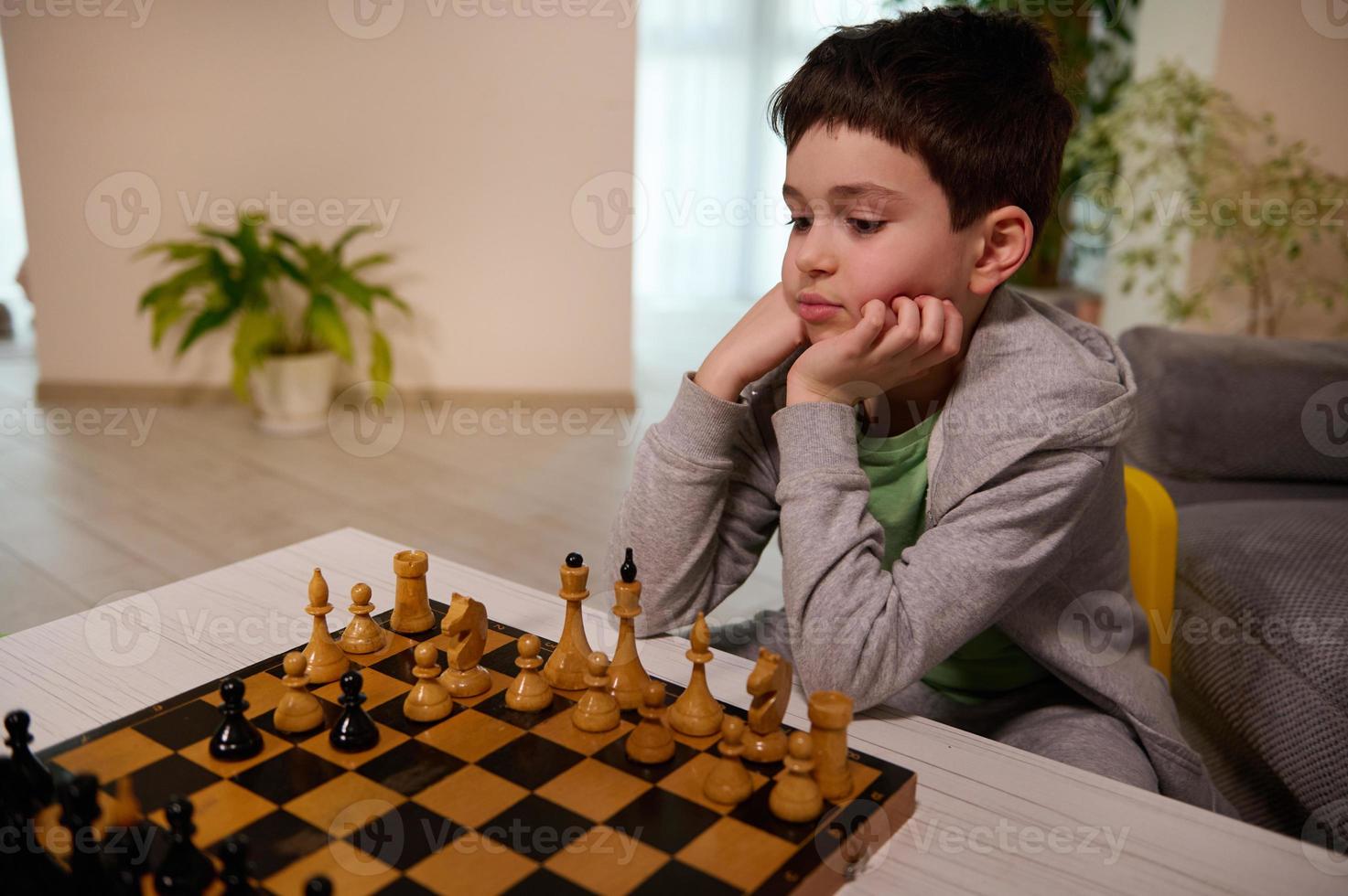 Concentrated Caucasian school aged boy developing chess strategy, playing board game with friend. Logic development, leisure board games, entertainment, intelligent hobby and education concept photo
