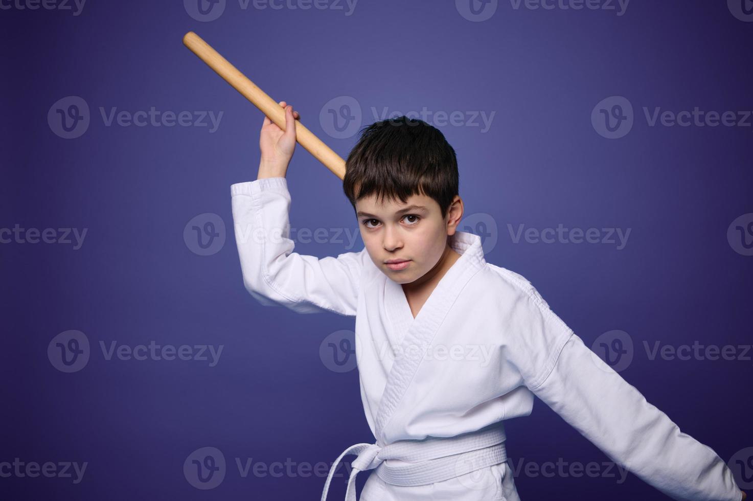 Confident charming European martial arts fighter poses with aikido wooden weapon, isolated on purple background, copy ad space for text photo