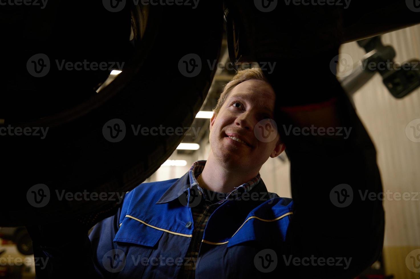 Mechanic checking the alignment of car checking the chassis using a lamp. Car engineer checking tire in maintenance service center. Technician or engineer professional work for customer photo