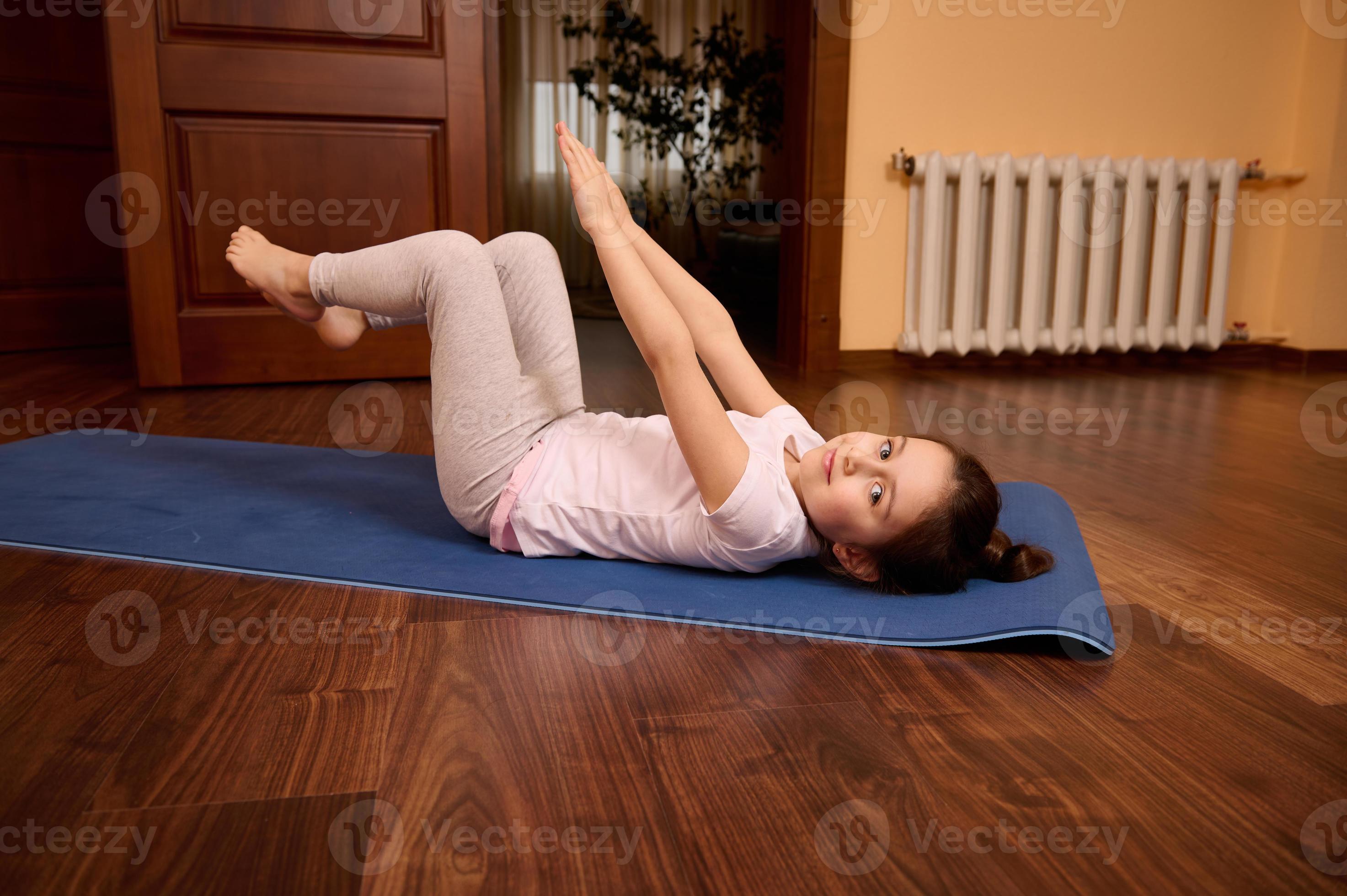 Happy relaxed Caucasian little child girl raising arms, doing abs  exercises, stretching body, lying on fitness mat 22971714 Stock Photo at  Vecteezy