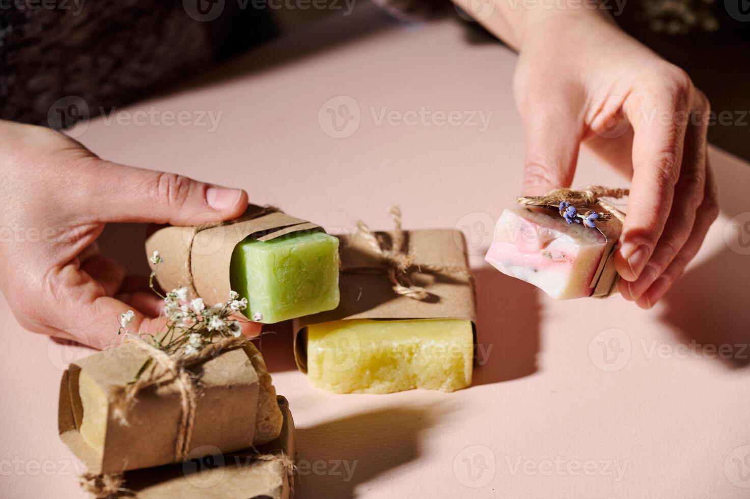 Close-up hands holding bars of homemade cold-pressed soap with essential oils and natural organic herbal ingredients photo