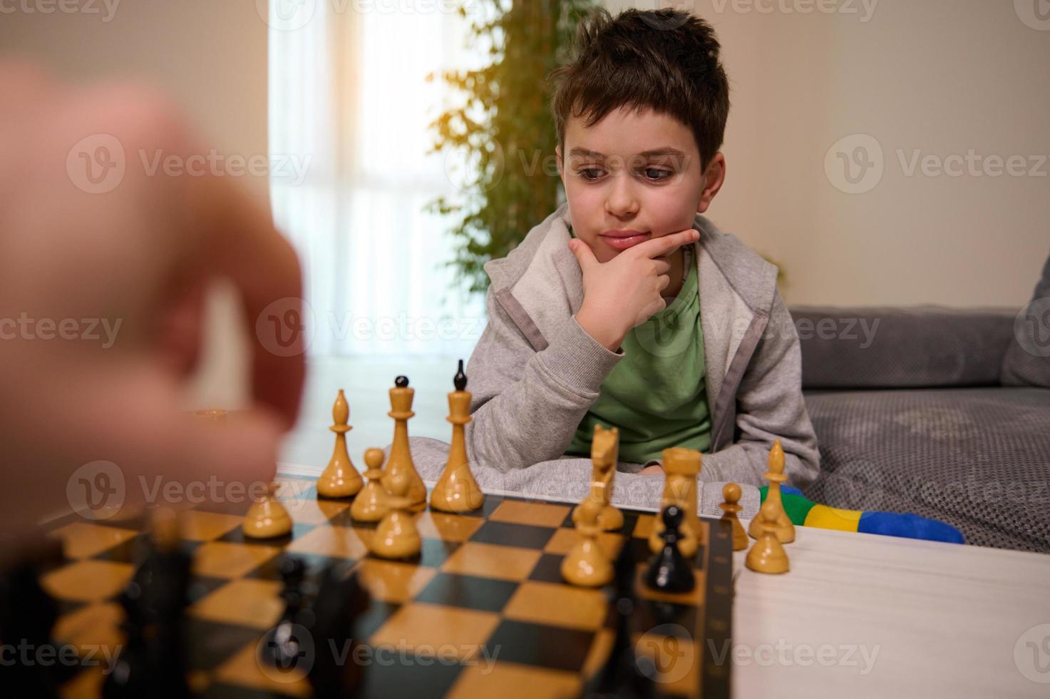 ajedrez juego para inteligente mente. hermoso inteligente pensativo Adolescente chico mirando pensativamente a ajedrez junta, pensando acerca de ajedrez estrategia mientras jugando foto