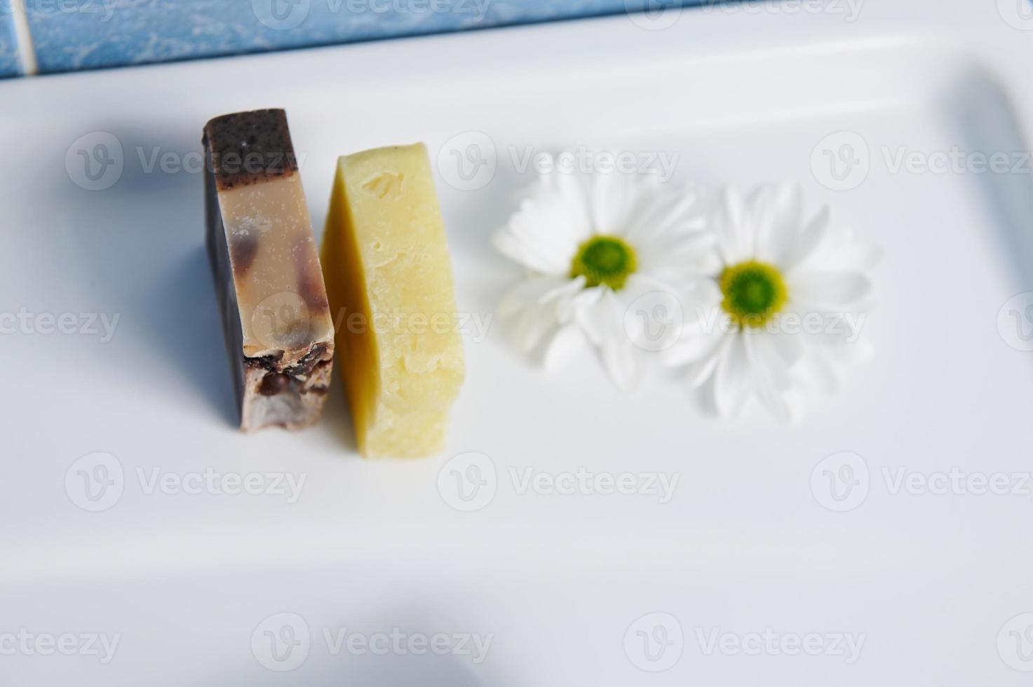 Top view organic hand made soap bars near chamomile flower on a washbasin. Natural cosmetics, hygiene and beauty concept photo