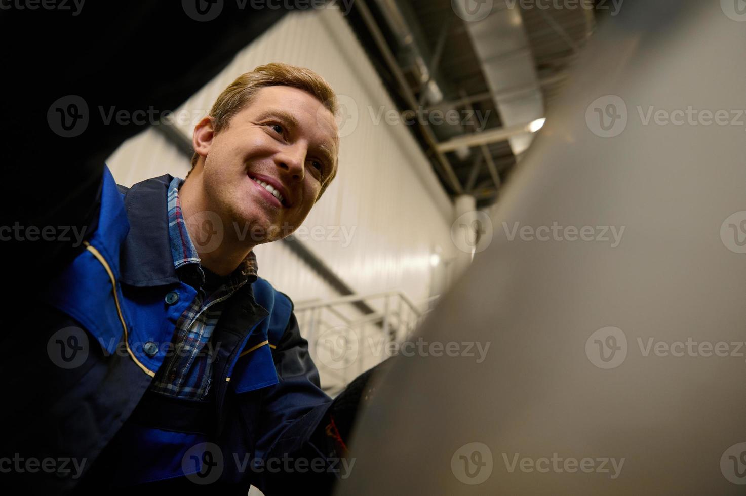 Close-up portrait of a garage mechanic working in repair shop, inspecting car engine during regular warranty vehicle maintenance photo