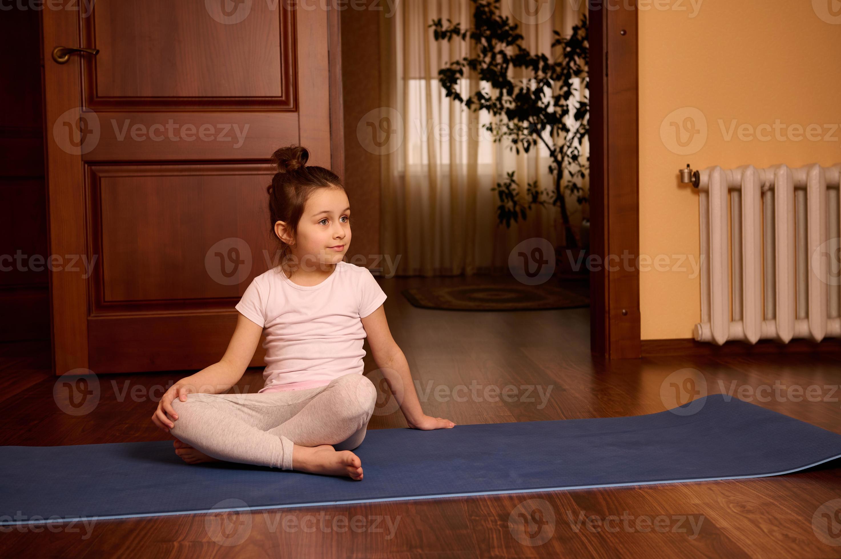 Adorable Caucasian 5 years old little child girl in active wear, sitting on yoga  mat at cozy home interior. 22972001 Stock Photo at Vecteezy