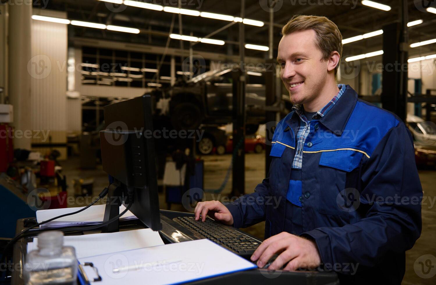 A technician, garage mechanic typing on keyboard, making checklist for repairing cars, conducting diagnostic check of a car during regular warranty maintenance in auto service photo