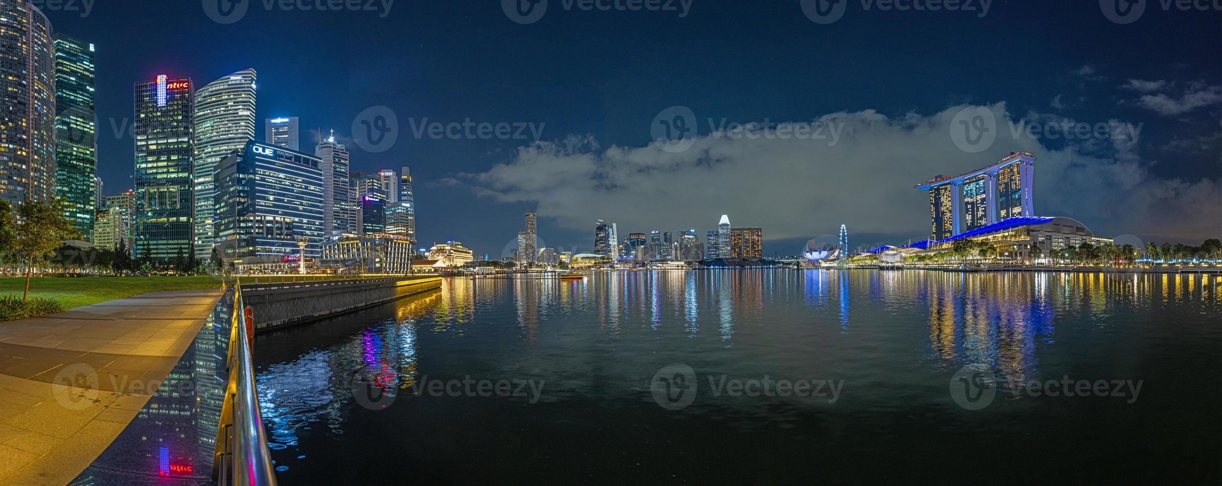 View over Marina Bay in Singapore durnig sunset with light illuminations in water photo