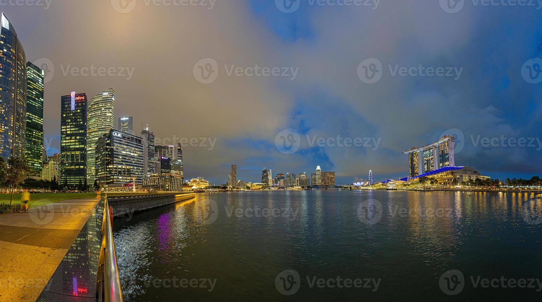 View over Marina Bay in Singapore durnig sunset with light illuminations in water photo