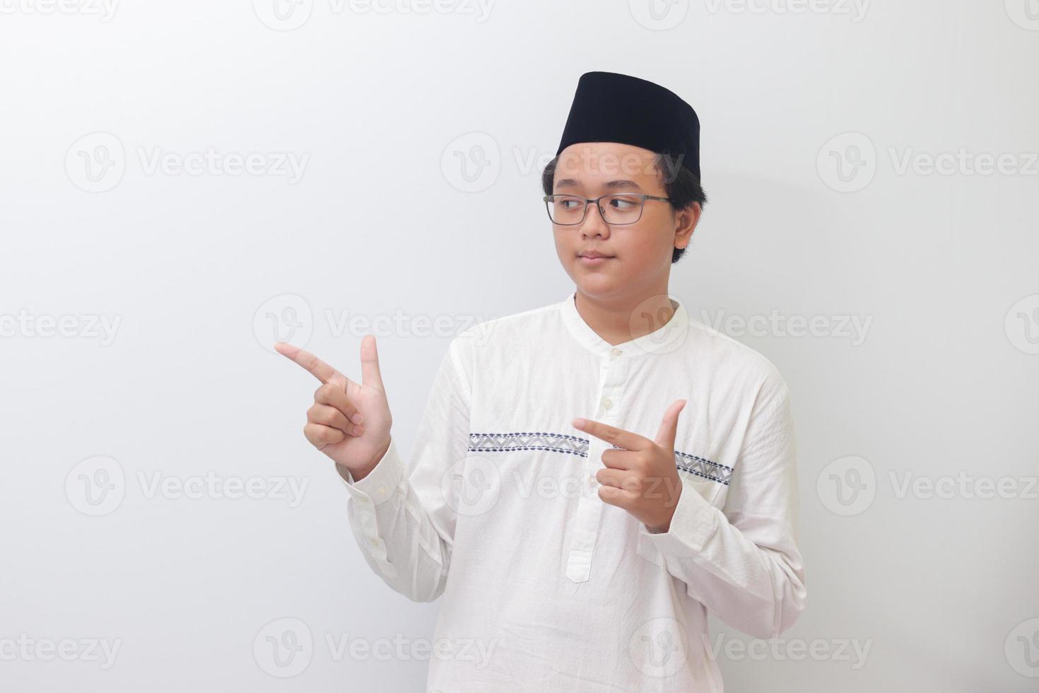 Portrait of young Asian muslim man showing product and pointing with his hand and finger. Isolated image on white background photo