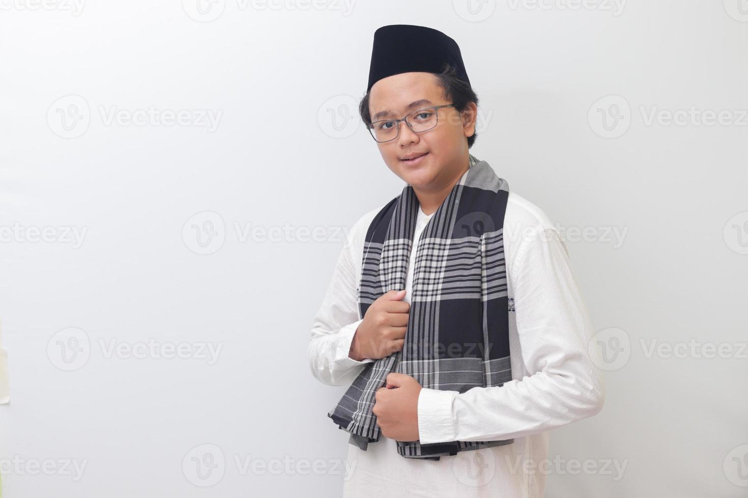 Portrait of young Asian muslim man standing with cool pose and holding his sarong. Isolated image on white background photo