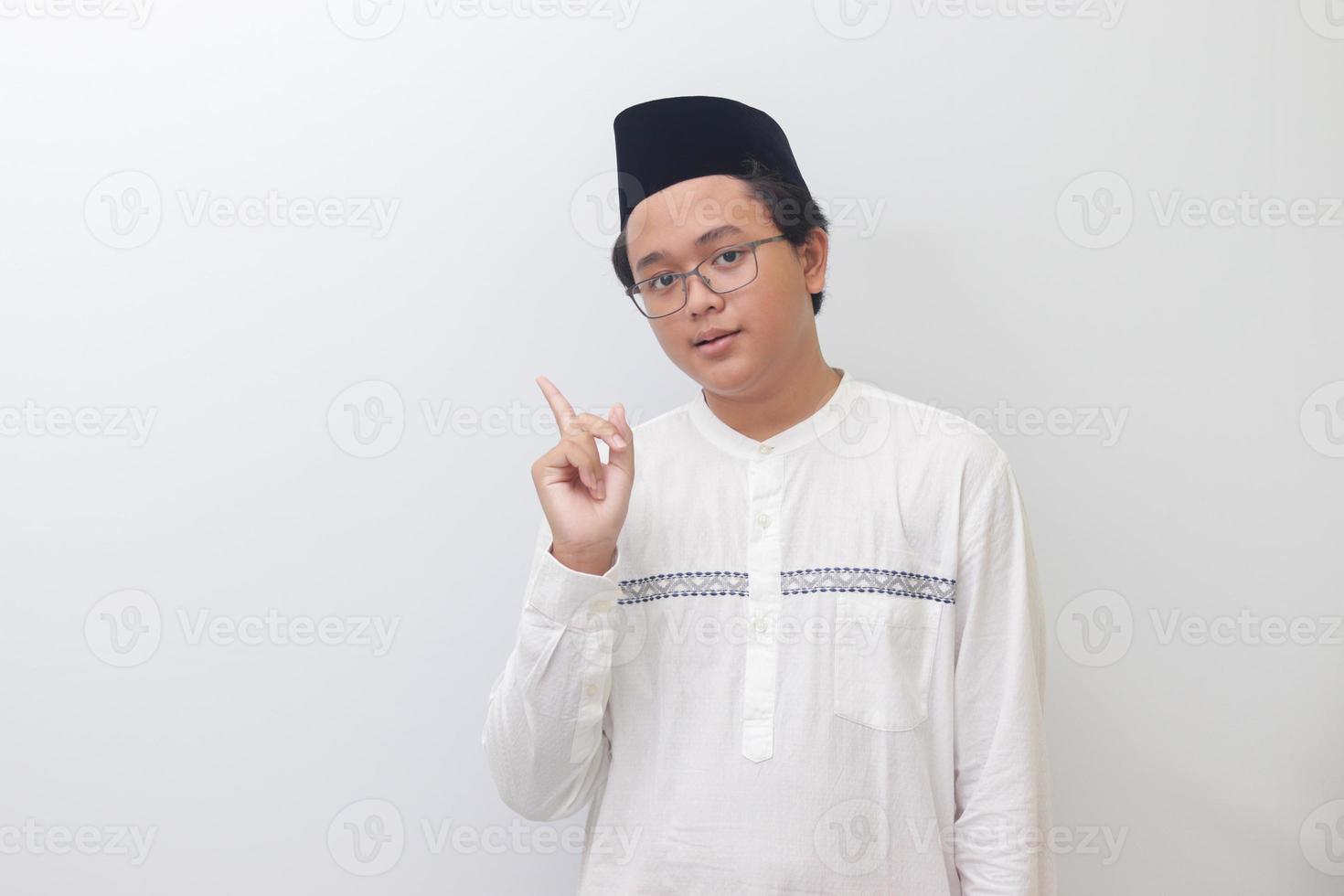 Portrait of young Asian muslim man showing product and pointing with his hand and finger. Isolated image on white background photo