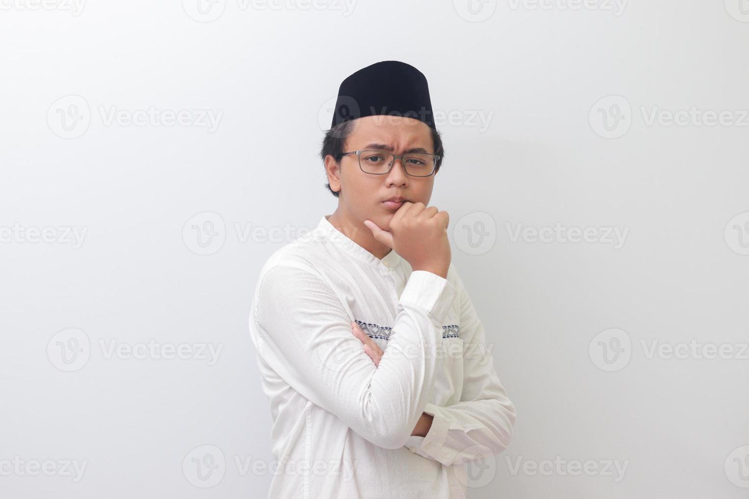 Portrait of young Asian muslim man thinking about question with hand on chin. Isolated image on white background photo