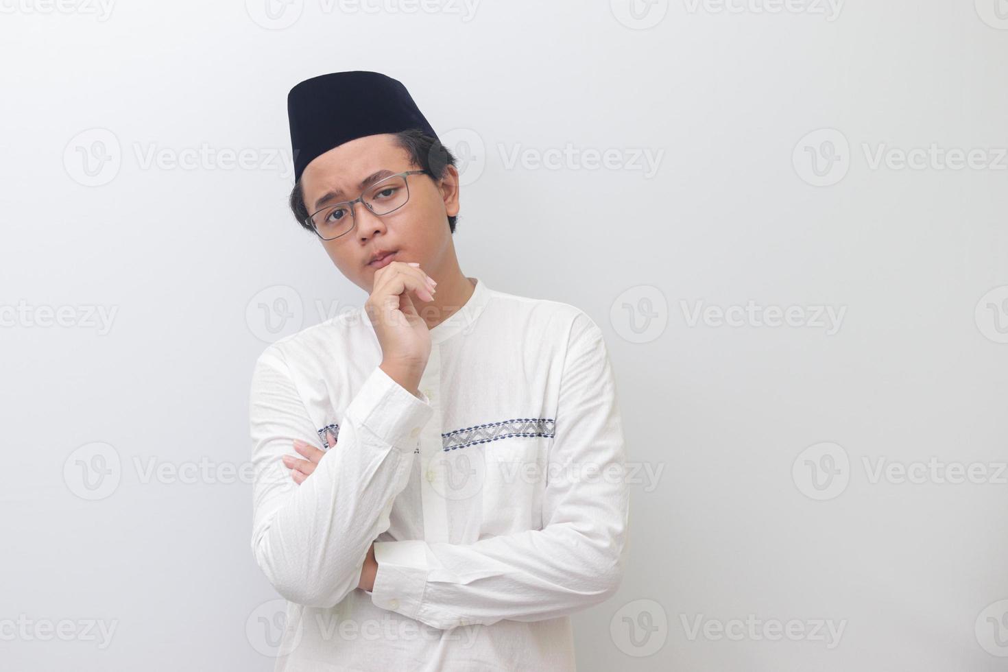 Portrait of young Asian muslim man thinking about question with hand on chin. Isolated image on white background photo