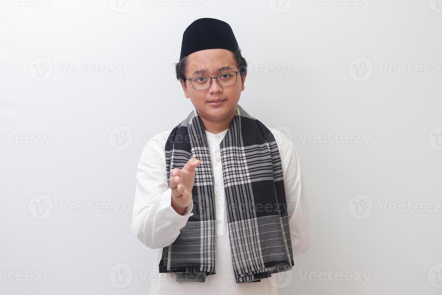 Portrait of young Asian muslim man reaching out his hand for a handshake. Isolated image on white background photo