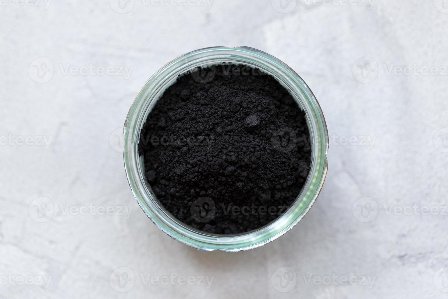 Black activated charcoal powder in a glass photo