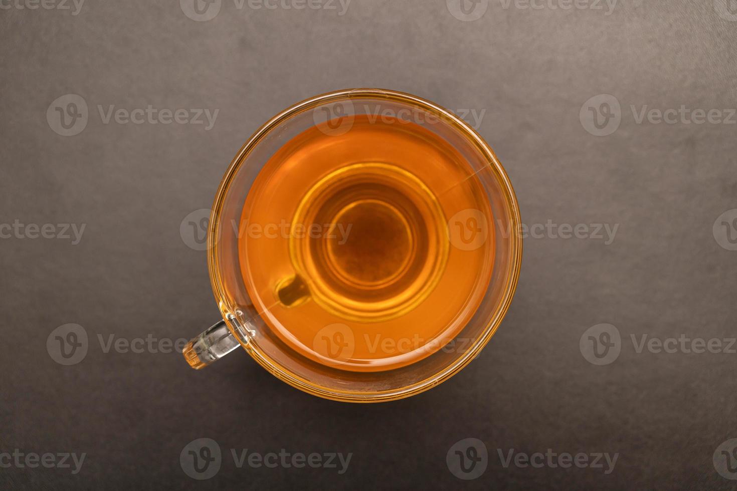 Glass cup of hot ginger tea on the black desk. photo