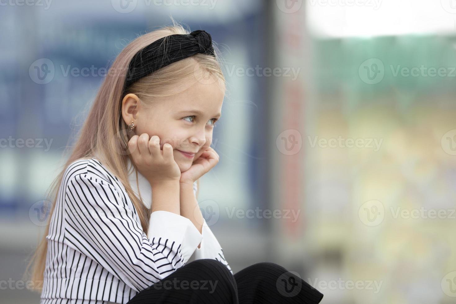 A beautiful little girl in an urban setting. A child of elementary age. photo