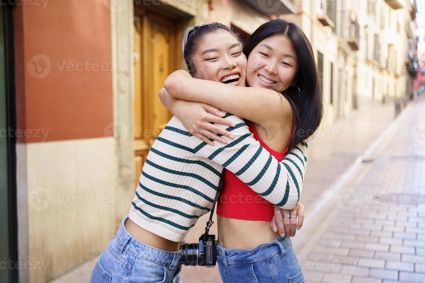 Asian girlfriends hugging on city street photo