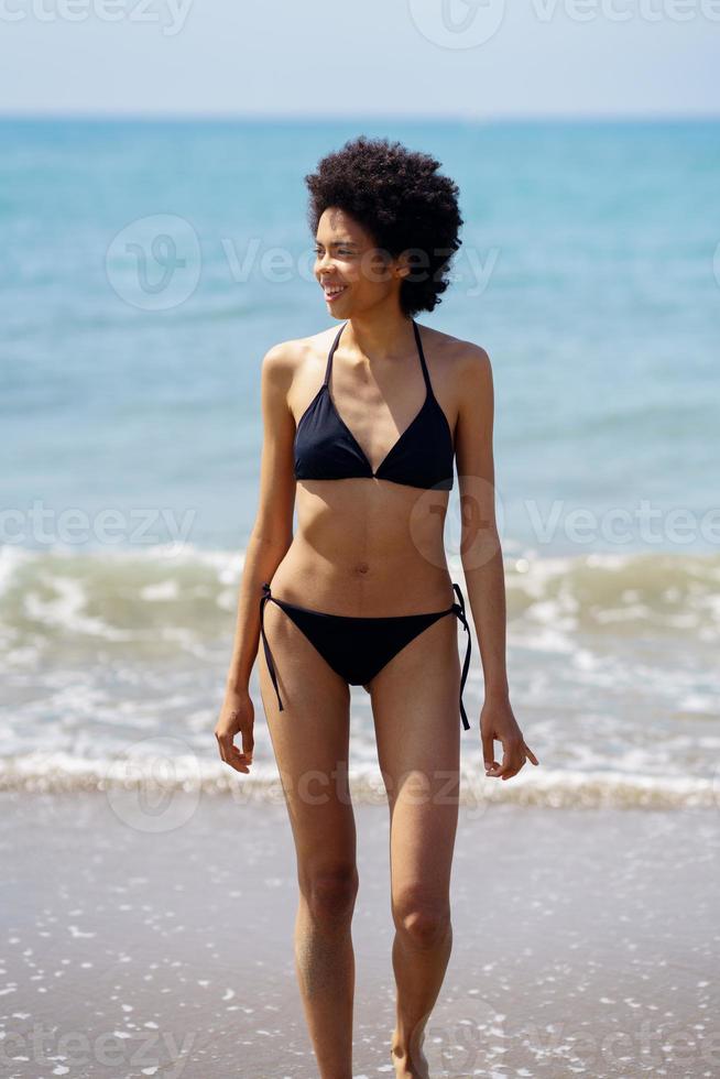 Positive black woman in swimwear near sea photo