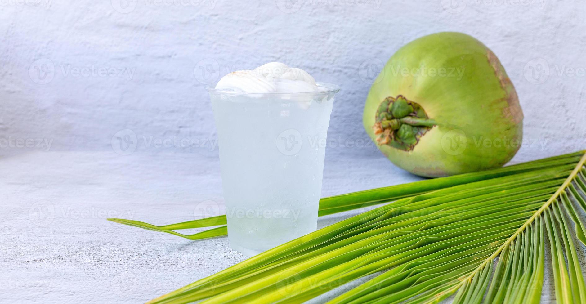 Ice coconut water drink in a plastic glass and coconut on white background photo
