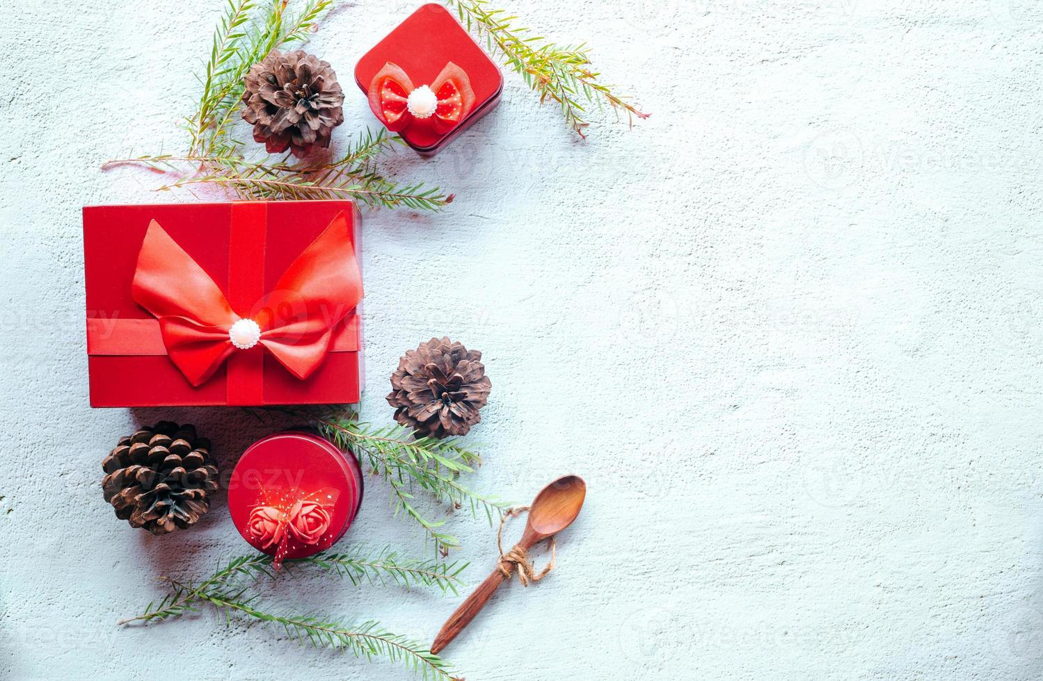 Christmas decoration composition on white background with a beautiful Red gift box with red ribbon, tree branches, and pine cones photo
