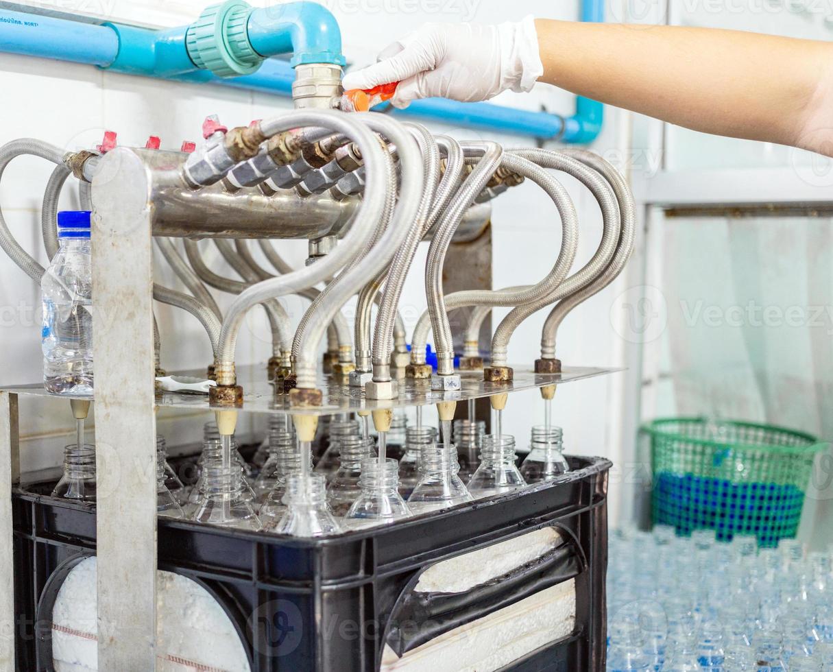 Bottling plant-Water bottling line for processing and bottling drink water into bottles. Bottle filling with drink water poured in a clear plastic bottle photo