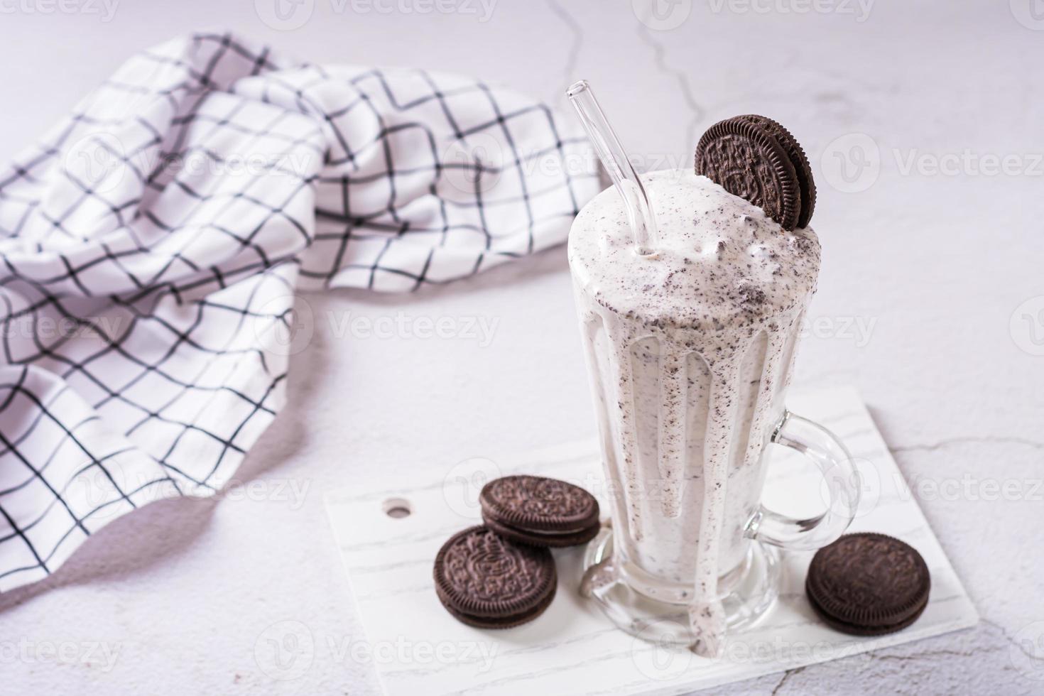 Homemade smoothie with cream and whipped chocolate chip cookies in a glass with a straw photo