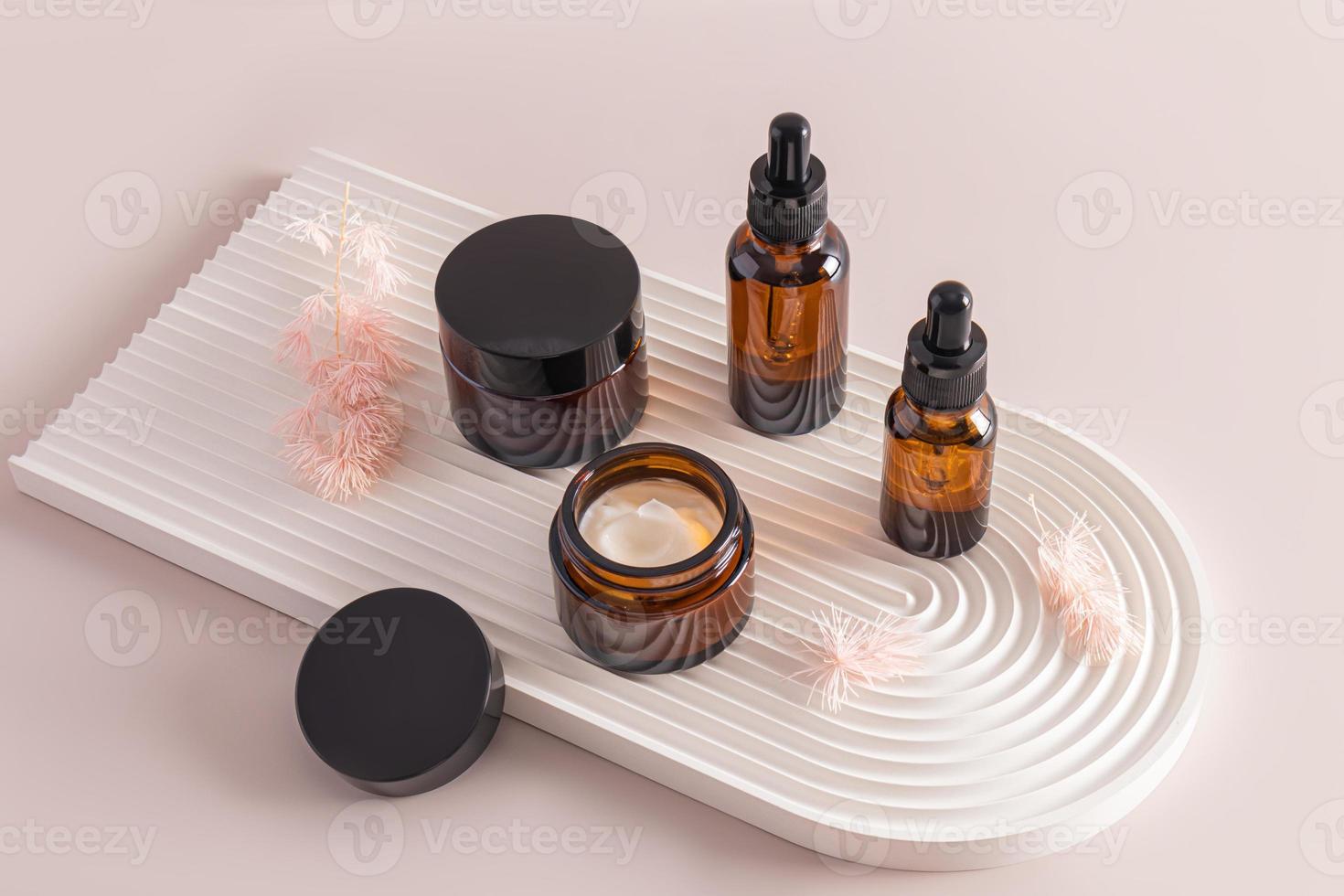 a set of various cosmetic bottles made of dark glass with cream and serum on a relief plaster podium in the form of an arch. natural care. photo