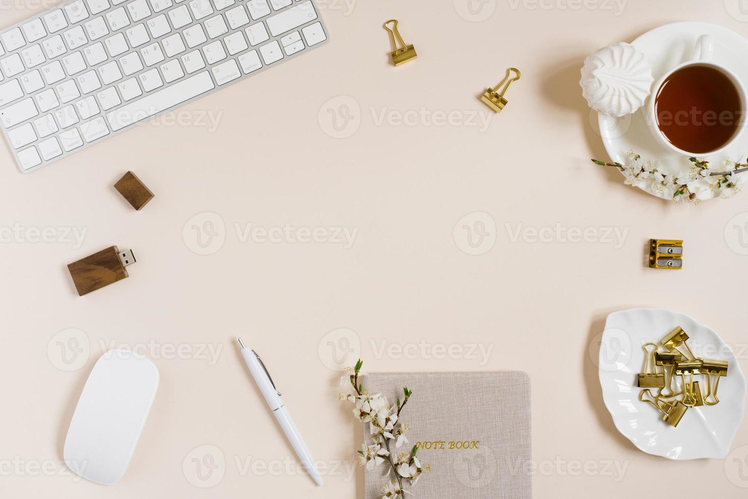 Feminine flat lay workspace with laptop, cup of tea, marshmallow and flowers on beige table. Top view mock up. photo