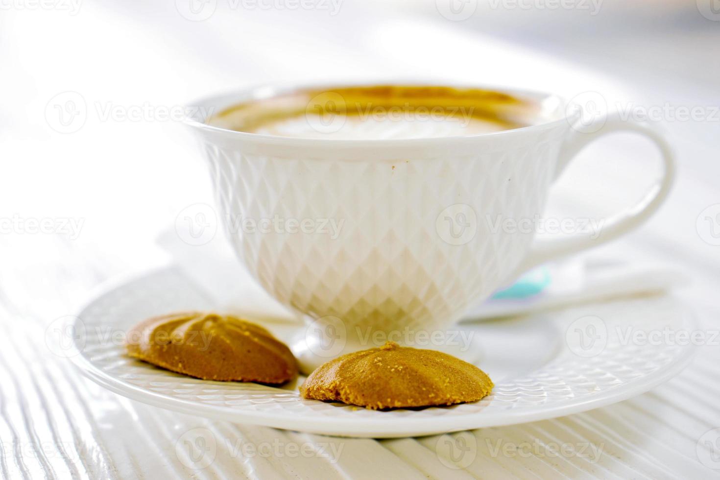 caliente latté café en un blanco café taza con galletas en blanco de madera mesa. foto