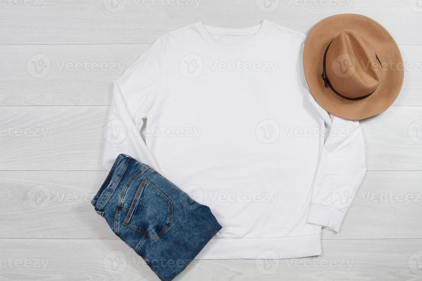 White Sweatshirt mockup. Template blank shirt top view on white wooden background. Winter outfit on wood floor. Woman fashion clothes. Spring look of today. Female Jeans, hat accessories photo