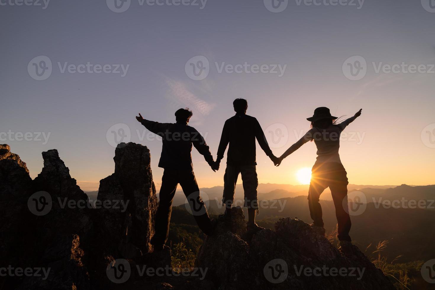 Silhouettes of three people climbing on mountain and helping. Help and assistance concept. photo