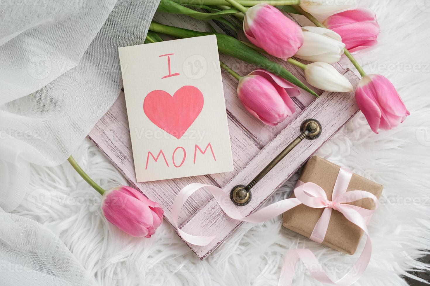 A bouquet of tulips and a card with the text I love mom on a tray. Mother's day concept photo